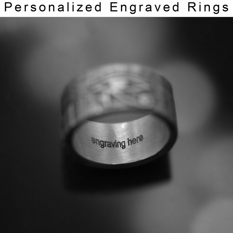 May include: A silver ring with a textured surface and the words "engraving here" inscribed on the inside.
