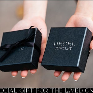 May include: Two black gift boxes with black ribbon. The larger box has the text "HEGEL JEWELRY" printed on the top.