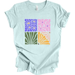 May include: A light blue t-shirt with a graphic design of four colorful stylized flowers in a square pattern.