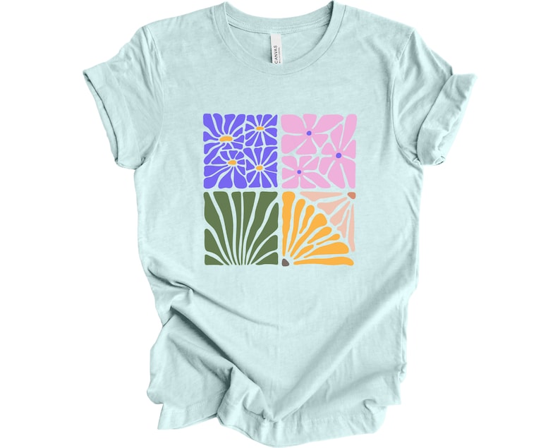 May include: A light blue t-shirt with a graphic design of four colorful stylized flowers in a square pattern.
