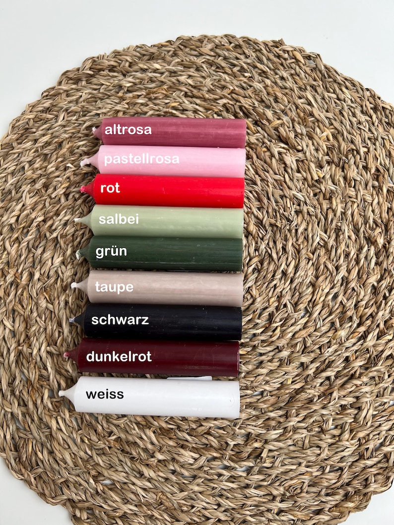 Neun Stabkerzen in den Farben altrosa, pastellrosa, rot, salbei, grün, taupe, schwarz, dunkelrot und weiß auf Untersetzer