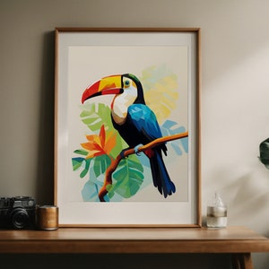 以下が含まれることがあります： 緑の葉のついた枝に止まっている、大きなオレンジ色のくちばしを持つオニオオハシの額装されたプリント。オニオオハシは青、黒、黄色で、背景は薄い青色で、黄色と緑のヒントがあります。