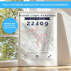 May include: A framed print displaying a Marine Corps Marathon finisher's map, personalized with the runner's name, race details, and time. The map features a red route over a gray city map, with the text "22409" prominently displayed. The text "26.2 MILES" is also visible.