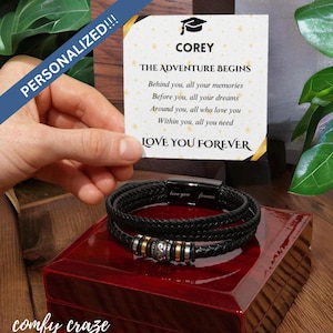 Puede incluir: Un brazalete de cuero negro con un dije de cuentas plateadas y doradas. El brazalete está en una caja roja con una tarjeta que dice "COREY THE ADVENTURE BEGINS Behind you, all your memories Before you, all your dreams Around you, all who love you Within you, all you need LOVE YOU FOREVER".