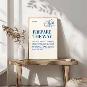 Op de afbeelding: Een beige printbare wandkunstprint met blauwe tekst die "Bereid de weg" luidt en een citaat uit Mattheüs 3:3. Het citaat luidt: "Dit is hij van wie gesproken is door de profeet Jesaja: Een stem die roept in de woestijn: 'Bereid de weg voor de Heer, maak zijn paden recht.'"