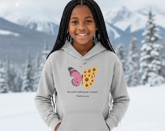 May include: A light gray hoodie featuring a butterfly design. One wing is pink with black details, the other is made of sunflowers. The text "The earth is full of your creatures Psalm 104:24" is printed below the butterfly.