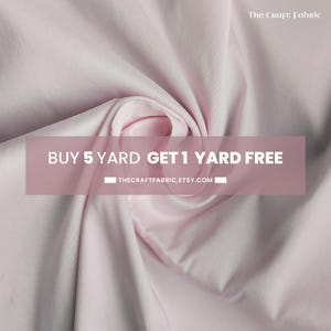 Puede incluir: Primer plano de una tela rosa claro con pliegues suaves y un brillo sedoso. La superposición de texto dice "COMPRA 5 YARDAS Y OBTÉN 1 YARDA GRATIS" con una dirección web. El logotipo de The Craft Fabric está en la esquina superior derecha.