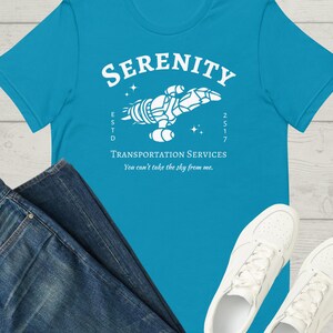 May include: A turquoise blue t-shirt with a white graphic of a spaceship with the text "Serenity Transportation Services" and "You can't take the sky from me."