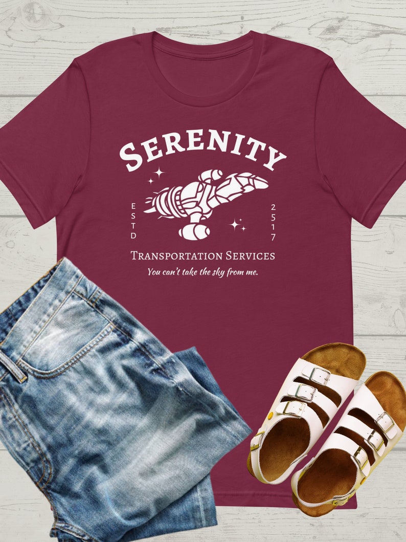 May include: A maroon t-shirt with a white graphic of a spaceship with the text "Serenity" above it and "ESTD 2517" below it. The text "Transportation Services" is below the spaceship and the text "You can't take the sky from me." is below that.