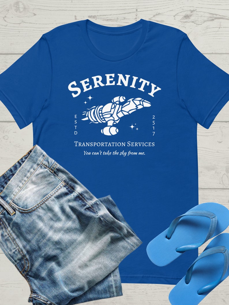 May include: A royal blue t-shirt with a white graphic of a spaceship with the text "Serenity" above it and "Transportation Services" below it. The text "Est'd 2517" is on the left side of the spaceship and the text "You can't take the sky from me." is below the text "Transportation Services".