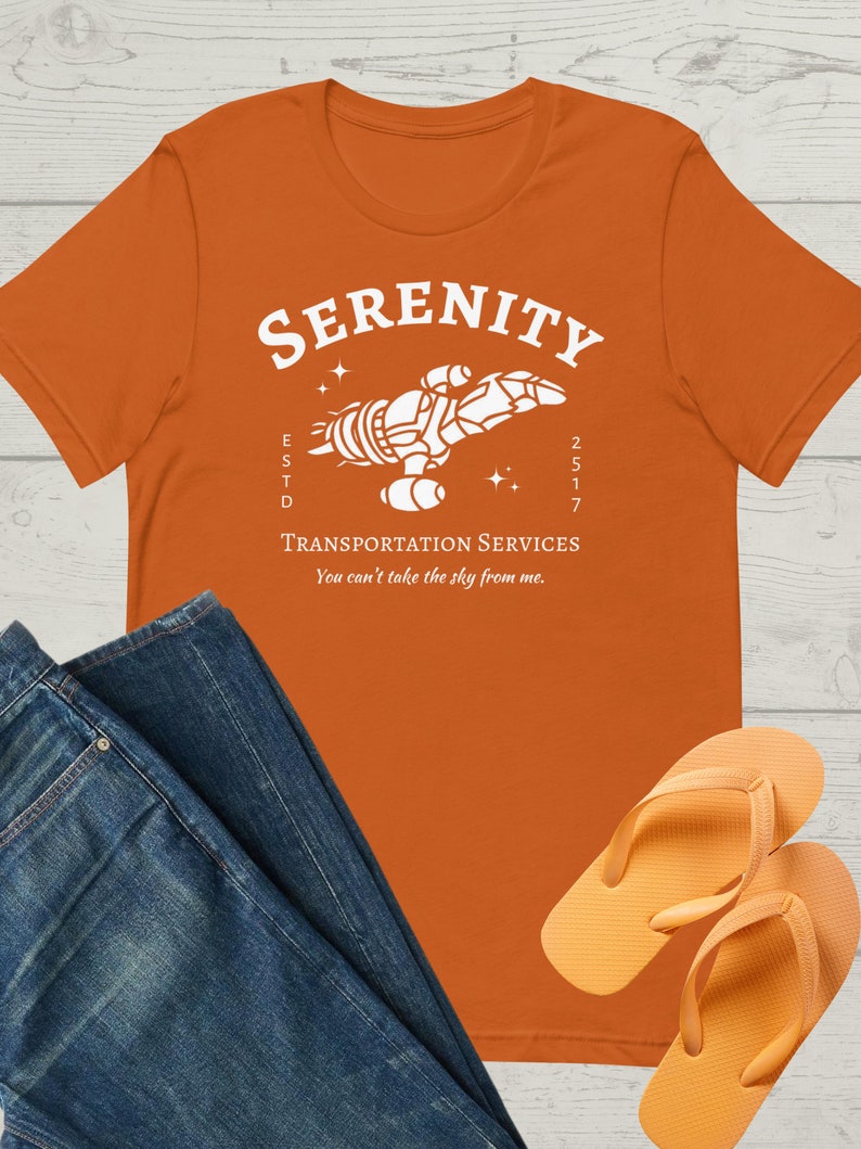 May include: Orange t-shirt with a white graphic of a spaceship with the text "Serenity Transportation Services" and "You can't take the sky from me."