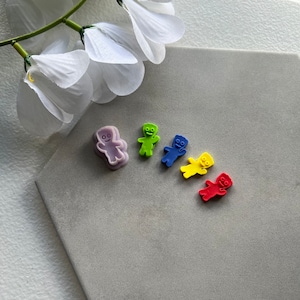 May include: Five gummy bear shaped cookie cutters, one purple, one green, one blue, one yellow, and one red.