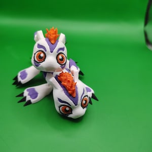 Pode incluir: Duas figuras brancas com detalhes roxos e laranja, que se assemelham a uma personagem de desenho animado. As figuras têm olhos grandes laranja, marcas roxas e cristas laranja. O fundo é verde liso.