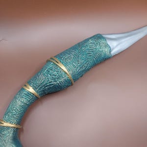 May include: A teal and gold dagger with a textured handle and a silver blade.