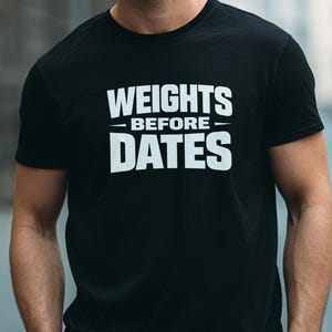 May include: Black t-shirt with the white text "WEIGHTS BEFORE DATES". The shirt has a crew neck and short sleeves. The text is centered on the chest.