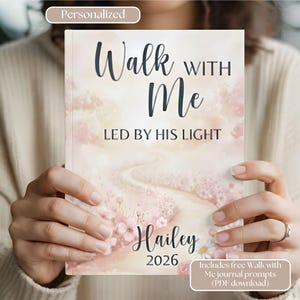 May include: A personalized journal titled "Walk With Me" with the text "Led By His Light" and the name "Hailey" and the year "2026". The cover features a watercolor design with a path and floral accents.