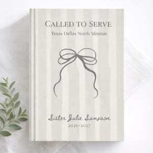 May include: A hardcover journal with a cream and gray striped design. The cover features the text "CALLED TO SERVE" and "Texas Dallas North Mission". Below is a gray bow illustration and the name "Sister Julie Sampson" with the dates "2026-2027".