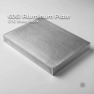 May include: A rectangular 6061 aluminum plate, CNC sheet stock, with a brushed metal finish. The plate is a solid, silver-gray color and has a smooth, even surface. The text "6061 Aluminum Plate" and "CNC Sheet Stock" is displayed on the top.