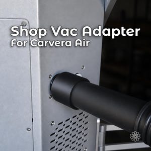 May include: A black cylindrical shop vac adapter attached to a silver machine housing. The text Shop Vac Adapter For Carvera Air is printed in white on the upper left side. The machine features a perforated vent panel and visible metal screws.