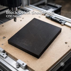 May include: A black Delrin sheet plate, CNC stock, is shown on a light brown surface. The text "Black Delrin Sheet Plate CNC Stock" is visible. A digital caliper and CNC machine components are in the background.