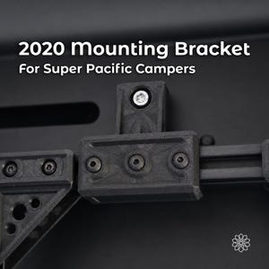 Könnte beinhalten: Eine schwarze Montagehalterung für Super Pacific Campers mit strukturierter Oberfläche und mehreren Sechskantschrauben. Der Text 2020 Mounting Bracket For Super Pacific Campers ist oben deutlich vor einem dunklen Hintergrund zu sehen.