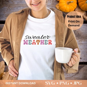 Pu&ograve; includere: Maglietta bianca con la scritta "Sweater Weather" in un font retr&ograve;. L'immagine mostra una persona che indossa la maglietta. Il testo aggiuntivo include "Project Idea Print On Demand" e "Instant Download SVG &bull; PNG &bull; JPG".