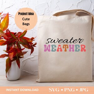 Pu&ograve; includere: Una borsa tote beige con la scritta "Sweater Weather" in nero e colori pastello. La borsa ha un design semplice con manici lunghi. L'immagine include anche un vaso con foglie autunnali e le parole "Project Idea Cute Bags".