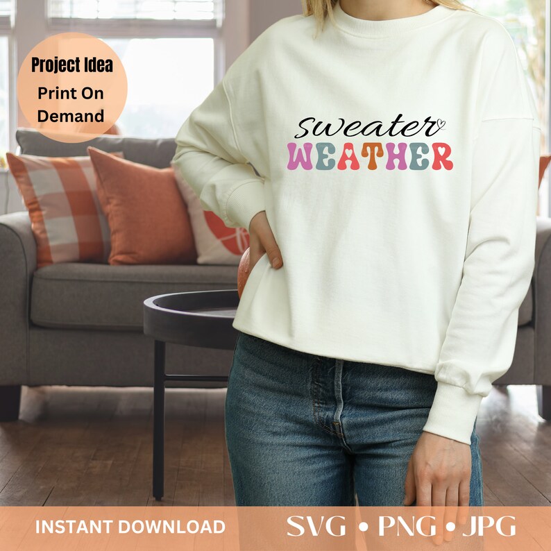 Pu&ograve; includere: Felpa color crema con la scritta "Sweater Weather" in un font retr&ograve;. La parola "Sweater" &egrave; in nero, e "WEATHER" &egrave; in rosa, blu, arancione e viola. La felpa &egrave; abbinata a jeans blu.