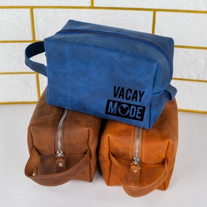May include: Three toiletry bags, one blue and two brown. The blue bag has the text "VACAY MODE" with a Mickey Mouse head icon.