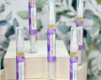 May include: Five clear plastic bottles with white caps and purple labels. The labels have floral designs and text that reads "Free Fragrance", "Coffee", "Lemon Eucalyptus", "Blue Grape", and "Spiced Vanilla".