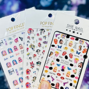 May include: Three packs of 3D nail stickers featuring various designs. The first pack has a pink, white, and black color scheme with a cartoon character design. The second pack has a pink, white, and black color scheme with a cartoon character design. The third pack has a pink, white, and black color scheme with a cartoon character design.