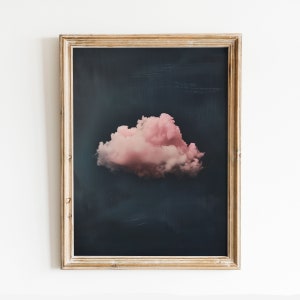 Puede incluir: Una impresión enmarcada de una sola nube rosa sobre un fondo azul oscuro.