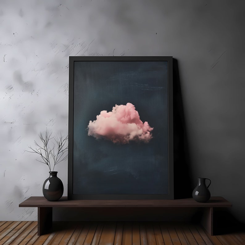 May include: A framed print of a single pink cloud against a dark blue background. The print is displayed on a wooden shelf with two black vases.