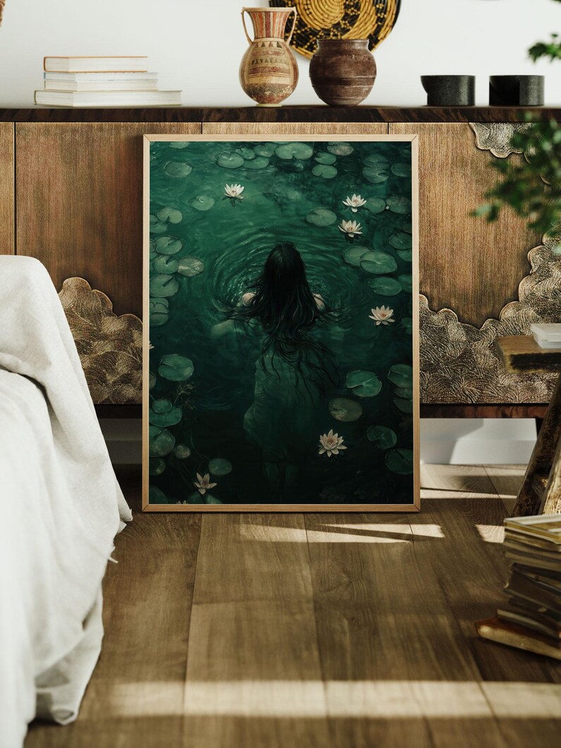 May include: A framed print of a woman swimming in a pond with white water lilies. The water is a deep green color and the woman's long dark hair is flowing behind her.