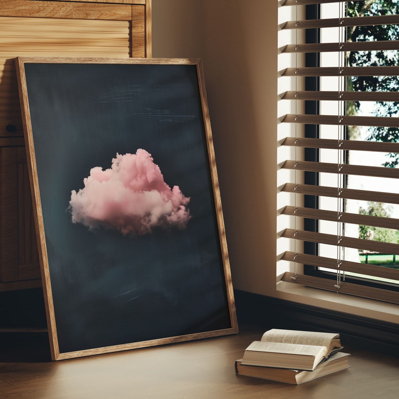 May include: A framed print of a pink cloud against a dark blue background. The print is hanging on a wall next to a window with wooden blinds.