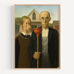 Op de afbeelding: Een ingelijste prent van de parodie van "American Gothic", met een man met een rode ontstopper en een vrouw die haar neus bedekt. Het kunstwerk is geplaatst tegen een achtergrond van een huis en boerderijgebouwen, met een houten frame.