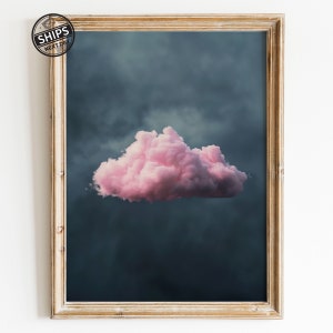 Puede incluir: Una sola nube grande y rosada contra un cielo azul oscuro. La nube es esponjosa y parece flotar en el aire.