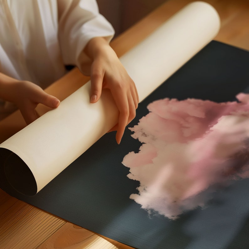 May include: A person unrolls a white poster tube to reveal a black poster with a pink watercolor design.