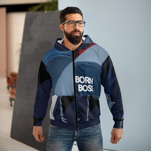 Op de afbeelding: Een zip-up hoodie met een patchwork denim design. De hoodie heeft een mix van blauwe denim tinten, zwart en witte panelen. De woorden "BORN BOSS" zijn in het wit op de voorkant gedrukt. De hoodie heeft een capuchon en een volledige rits.