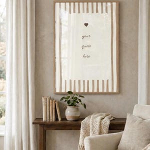 May include: A framed print with a neutral colour scheme. The artwork displays vertical stripes and the text "your quote here" with a heart symbol. The scene includes a wooden table with books and a plant, and a beige armchair.