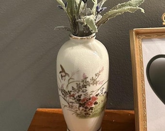 May include: A white ceramic vase with a floral design and a gold rim, filled with lavender sprigs.