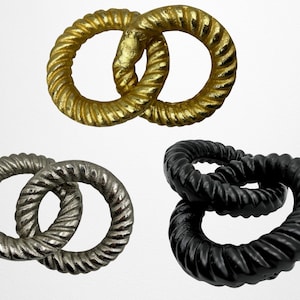 May include: Three sets of linked rings, each set with two rings. The first set is gold, the second is silver, and the third is black.