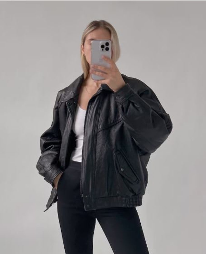 May include: A black leather jacket with a zipper closure and a stand-up collar. The jacket has a zippered pocket on the left side and a snap closure at the bottom.