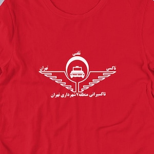 May include: Red t-shirt with a white graphic of a winged symbol with a car inside a circle. The text "قاسم آفرینی، منطقه شهر یاری تهران" is below the symbol.