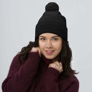 May include: Black beanie with a fluffy pom pom on top. The beanie has the text "BASICALLY" with "W/F" underneath in white.