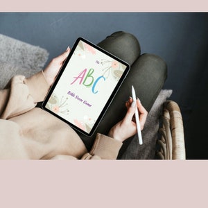May include: A digital tablet displaying a colourful alphabet with the text "The ABC Bible Verse Game". The tablet is held by a person with a white stylus.