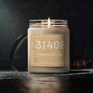 May include: A beige candle with a glass jar and a label that says "31408 savannah, ga".
