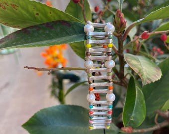 May include: A silver bracelet with colorful beads and white pearls. The bracelet has a black string attached to it.