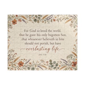 Op de afbeelding: Een rechthoekige legpuzzel met een crèmekleurige achtergrond en een rand van aquarel-stijl wilde bloemen in oranje, groene en paarse tinten. De tekst luidt: For God so loved the world, that he gave his only begotten Son, that whosoever believeth in him should not perish, but have everlasting life. John 3:16.