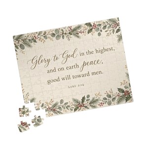 Puede incluir: Un rompecabezas rectangular con fondo crema y un borde de ramas de pino, hojas de eucalipto y bayas rojas. El texto dice: Glory to God in the highest, and on earth peace, good will toward men. Luke 2:14.
